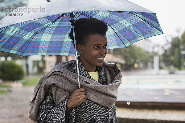 Italien  Grado  lächelnde Frau mit Regenschirm an einem regnerischen Tag