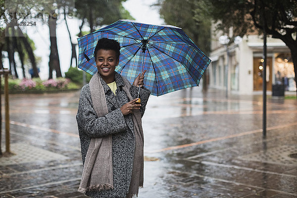 Italien  Grado  lächelnde Frau mit Regenschirm an einem regnerischen Herbsttag