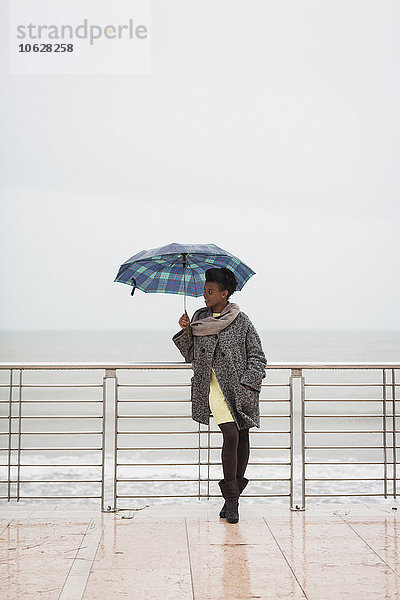 Italien  Grado  Frau mit Schirm vor dem Meer stehend
