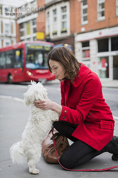 UK  London  junge Frau kniend auf dem Bürgersteig von Angesicht zu Angesicht zu ihrem Hund