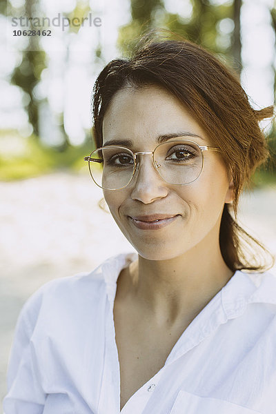 Porträt einer lächelnden Frau mit braunen Haaren und Brille