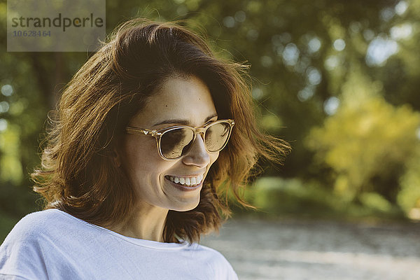 Porträt einer lächelnden Frau mit braunen Haaren und Sonnenbrille