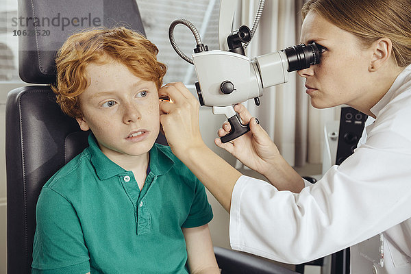 Ärztin untersucht kleinen Jungen mit Mikroskop