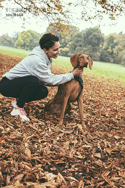 Frau im Gespräch mit ihrem Vizsla-Hund im Park im Herbst