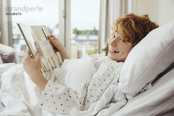 Kranker Junge liest Buch im Krankenhausbett liegend