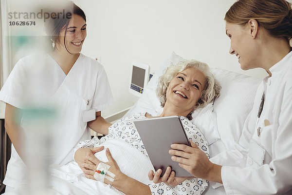 Seniorin im Krankenhaus im Gespräch mit Arzt und Krankenschwester
