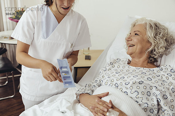 Krankenschwester erklärt ältere Frau im Krankenhaus Medikamente