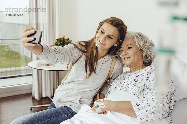 Enkelin besucht Großmutter im Krankenhaus  nimmt Selfie mit Smartphone