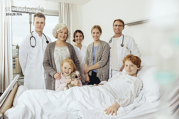 Ärzte und Familie im Krankenhaus stehen am Bett des kranken Jungen