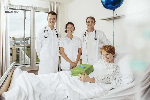 Ärzte im Krankenhaus stehen am Bett des kranken Jungen an seinem Geburtstag