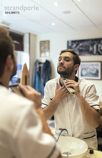 Barbier beim Rasieren seines Bartes in einem Friseurladen