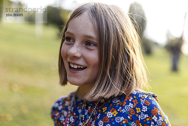 Porträt eines lächelnden blonden Mädchens mit Sommersprossen