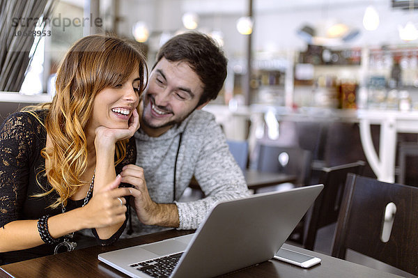 Glückliches junges Paar mit Laptop in einer Kneipe