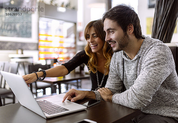Glückliches junges Paar mit Laptop in einer Kneipe