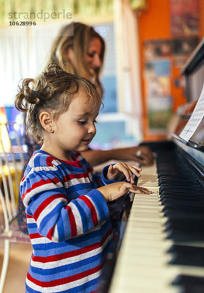 Frau und kleines Mädchen beim gemeinsamen Klavierspielen