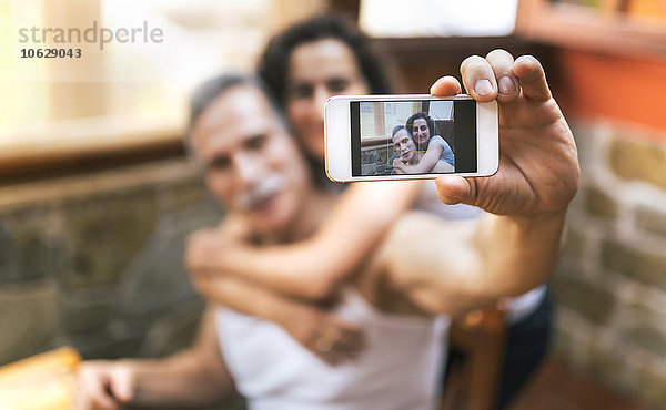 Foto des Paares  das einen Selfie auf dem Display des Smartphones nimmt.