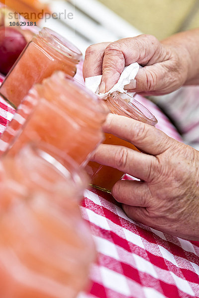 Seniorin wischt ein Glas hausgemachtes Apfelmus  Nahaufnahme