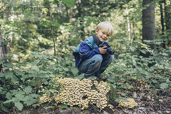 Deutschland  Sachsen  lächelnder Junge mit Kamera im Wald