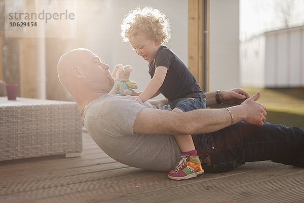 Vater spielt mit kleiner Tochter auf der Terrasse