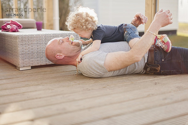 Vater spielt mit kleiner Tochter auf der Terrasse