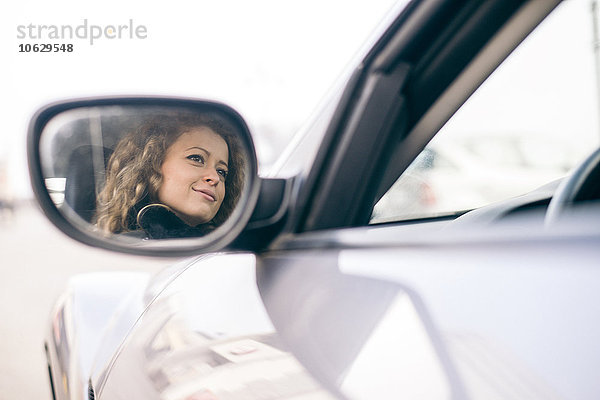 Frau fährt Auto  gespiegelt im Außenspiegel