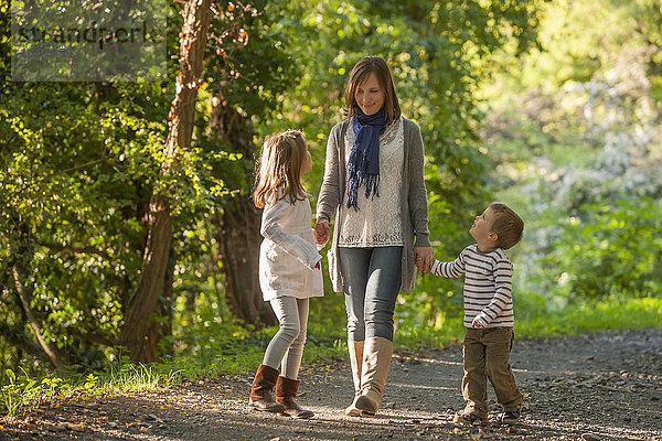 Mutter wandert mit ihren Kindern auf einem Waldweg