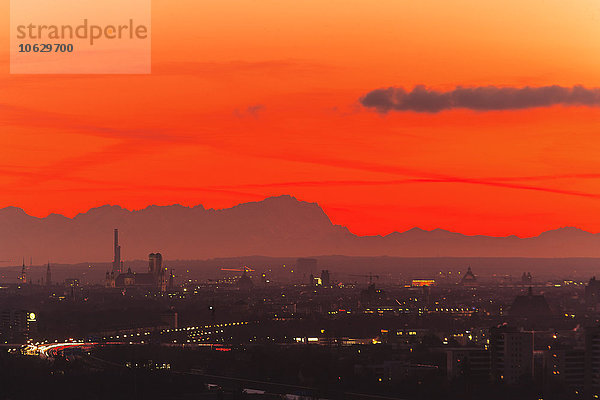 Deutschland  Bayern  München  Stadtbild bei Sonnenuntergang mit Alpen im Hintergrund
