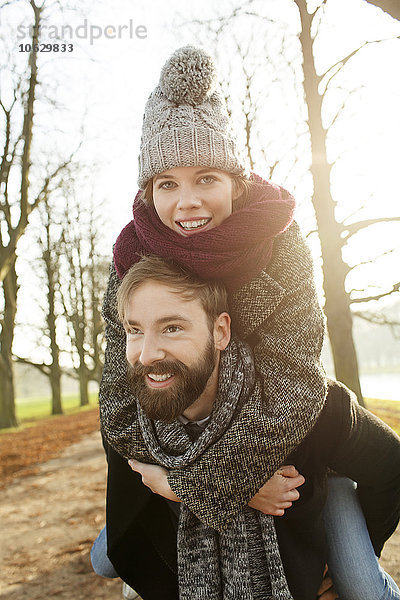 Junger Mann mit Freundin Huckepack im Herbst