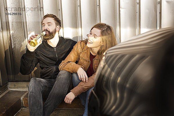 Glückliches Paar mit Bierflasche zum Entspannen in der Garage