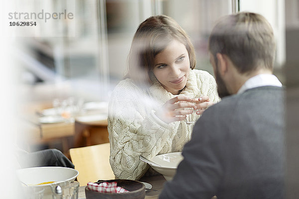 Lächelnde junge Frau schaut den Mann am Restauranttisch an.