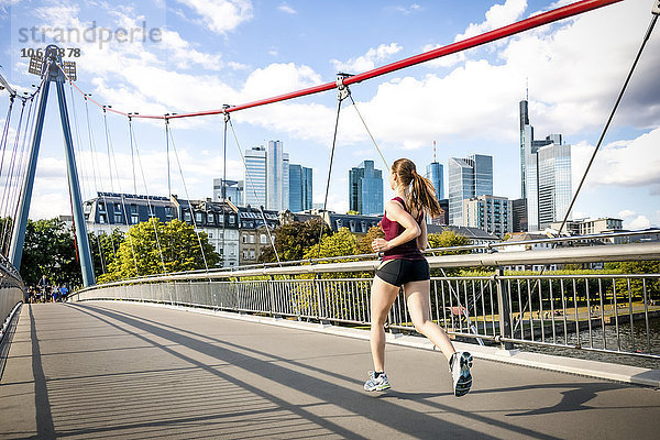 Deutschland  Frankfurt  junge Frau beim Joggen auf der Brücke
