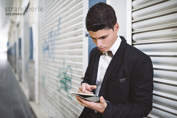 Junger Mann mit Jacke und Fliege aus Holz mit digitalem Tablett