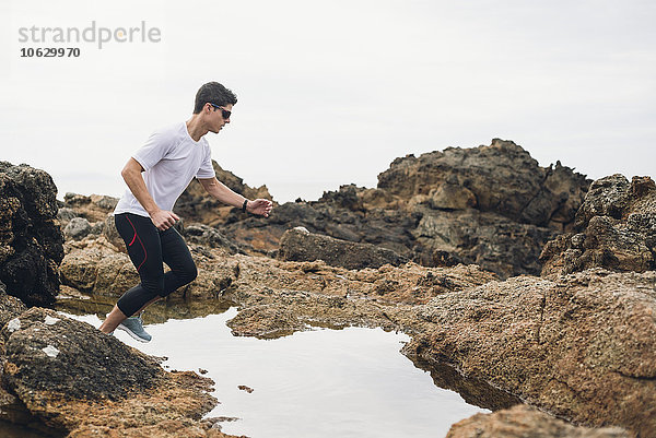 Spanien  Ferrol  Jogger bereit zum Sprung über Wasser an der Küste