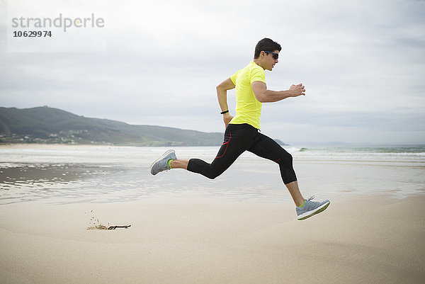 Spanien  Ferrol  junger Mann  der am Strand rennt