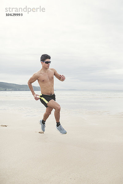 Spanien  Ferrol  ein junger Mann  der schnell am Strand rennt.