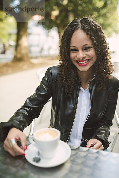Porträt einer lächelnden jungen Frau mit einer Tasse Kaffee