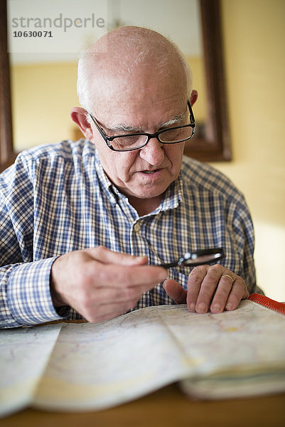 Älterer Mann beim Betrachten einer Straßenkarte mit Lupe