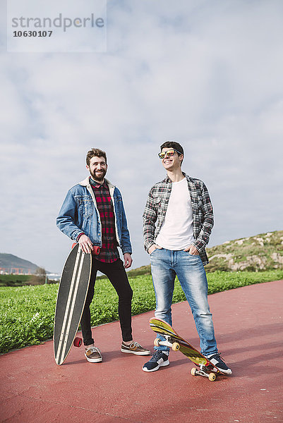 Zwei glückliche Freunde mit Longboard und Skateboard