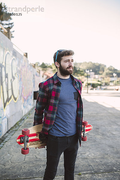 Spanien  La Coruna  Porträt des Hipsters mit seinem Longboard
