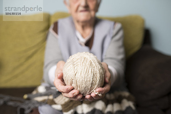 Hände der älteren Frau mit Wollknäuel