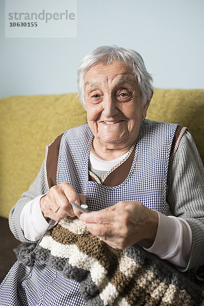 Porträt der lächelnden Seniorin beim Stricken