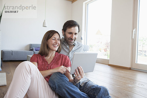 Erwachsenes Paar auf dem Boden sitzend  mit digitalem Tablett