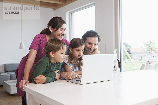 Glückliche Familie beim gemeinsamen Surfen im Internet mit dem Laptop