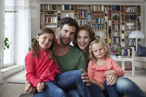 Familienporträt eines Paares mit zwei kleinen Mädchen auf dem Boden des Wohnzimmers