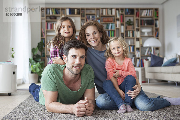 Familienporträt der Familie mit zwei kleinen Mädchen auf dem Boden des Wohnzimmers