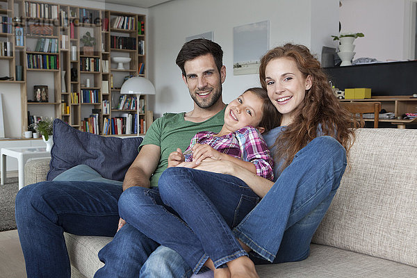 Portrait des glücklichen Paares und der kleinen Tochter auf der Couch zu Hause