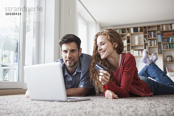 Glückliches Paar auf dem Boden liegend online einkaufen