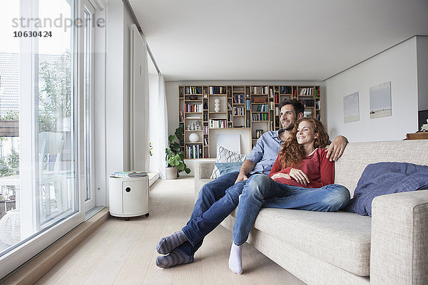 Entspanntes Paar zu Hause auf der Couch mit Blick aus dem Fenster