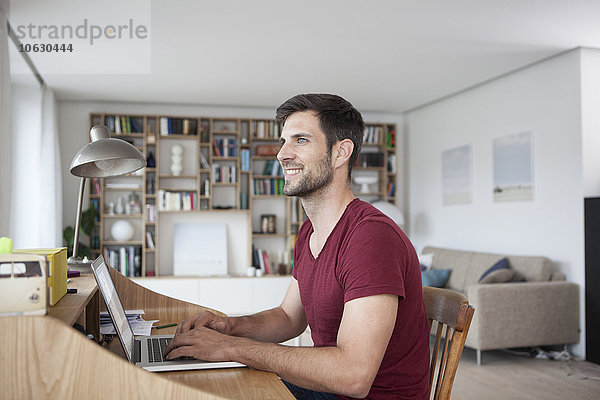 Lächelnder Mann zu Hause mit Laptop