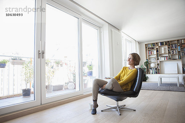 Entspannte Frau zu Hause auf Lederstuhl sitzend